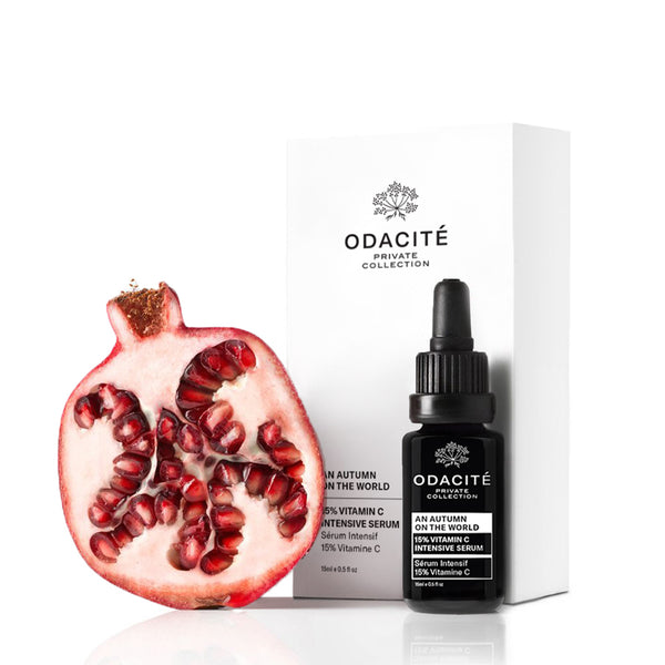 Halved pomegranate next to Odacite An Autumn On The World 15% Vitamin C Serum and its white box on a white background.
