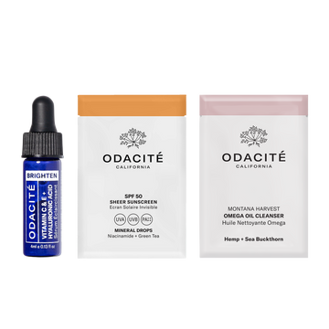 Odacité April Deluxe Samples with vitamin C serum vial, sunscreen packet, and omega oil cleanser bottle on a white background.
