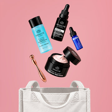 Odacité Fall Reset Box with Vitamin C skincare and a facial tool sits on a white bag, set against a pink background.
