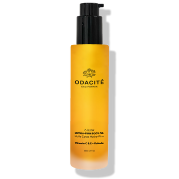 Yellow Odacité Free Gift C-Glow Hydra-Firm Body Oil bottle with black pump on a white background.