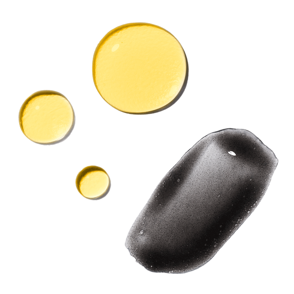 Three golden oil drops beside a grey clarifying cleanser smear from the Odacité Double Cleansing Set (Omega Oil + Clarifying Cleansers).