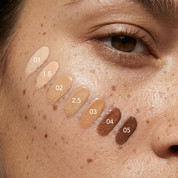 Odacité SPF 50 Tinted Mineral Drops swatches (01-05) on a freckled cheek near a brown eye.