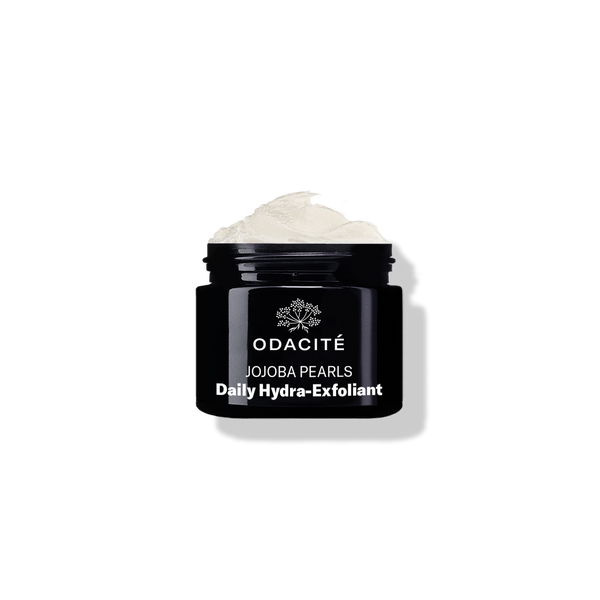Open black jar labeled Odacité Jojoba Pearls • White + Rooibos Tea Daily Hydra-Exfoliant with gentle exfoliant visible inside.