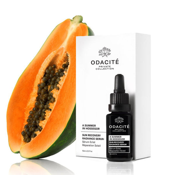 Half a papaya beside a white Odacité box and Corrective Repair Serum • A Summer in Hossegor, with clear product labels visible.