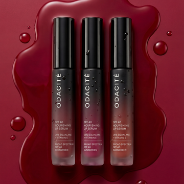 Odacité SPF 40 Nourishing Lip Serum Trio in upright tubes on a red background, with glowing serum drops around them.