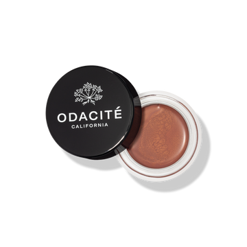 Open jar of Odacite cream with black lid on a white background