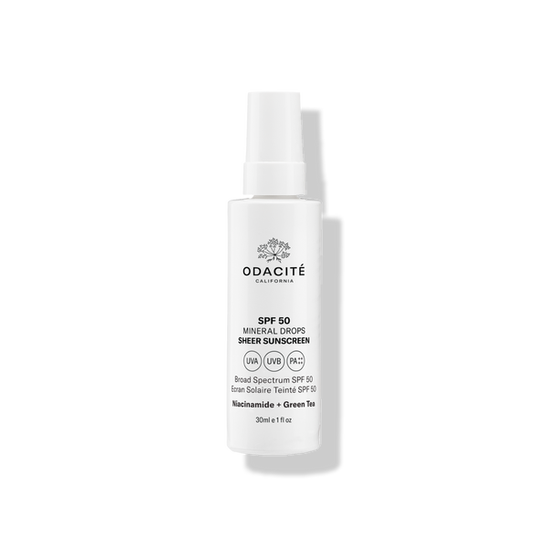 Odacité Mineral Drops SPF 50 Sheer Sunscreen with Niacinamide & Green Tea in a white bottle, labeled broad spectrum.