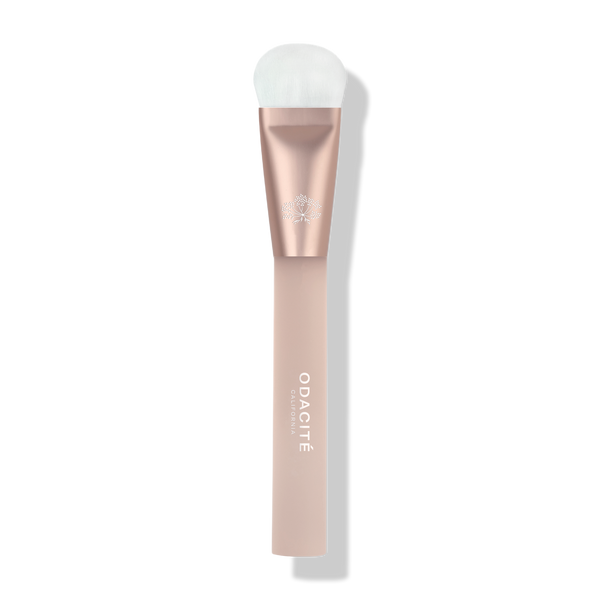 Odacité Universal Brush with white bristles and a rose gold and blush pink handle, shown on a plain background.