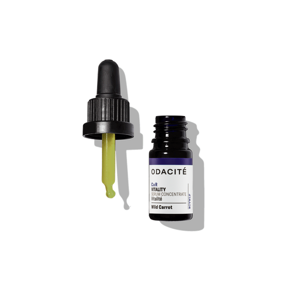 Odacite Wild Carrot CaR Serum Concentrate with dropper releasing yellow oil onto a white background.