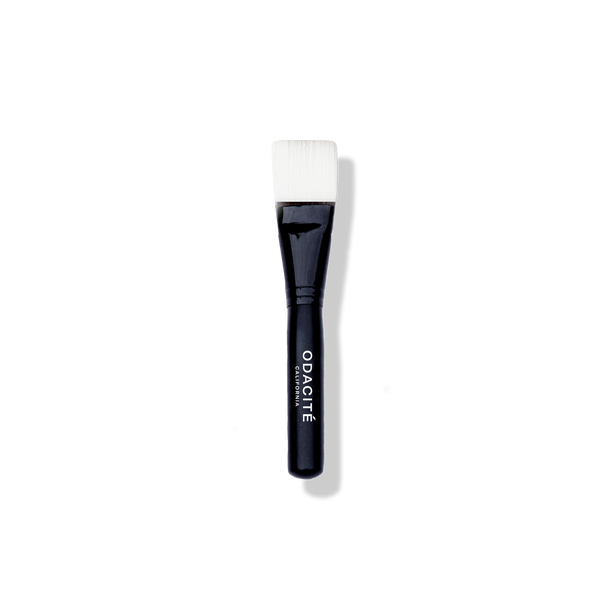 The Odacité Facial Brush with a black handle and soft vegan bristles, designed for applying face masks.