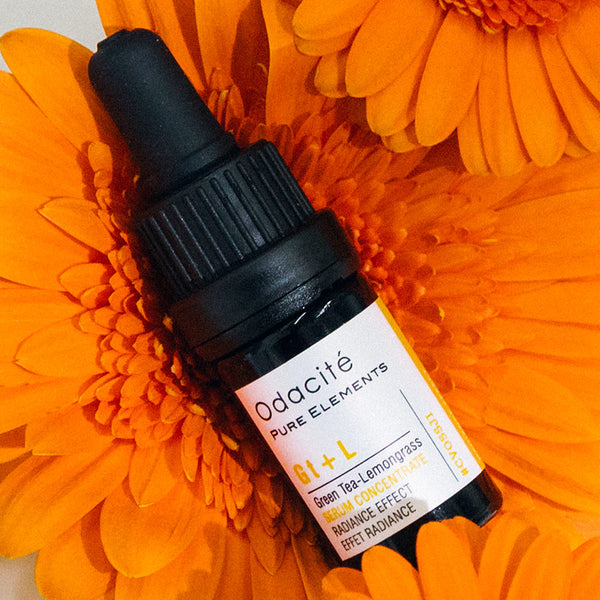 Odacite's Brighten + Balance Uneven Skin Duo placed on bright orange gerbera daisy petals.