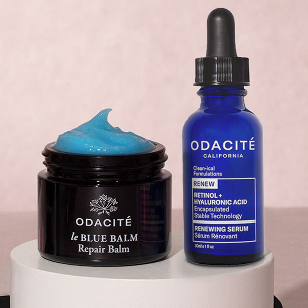 Odacité Clean-ical Repair Duo in clear bottles with white caps on a white round platform against a neutral background.